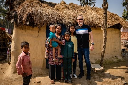 Pastor Dennis with a family outside their mud-and-thatch home in the village of Balchaur