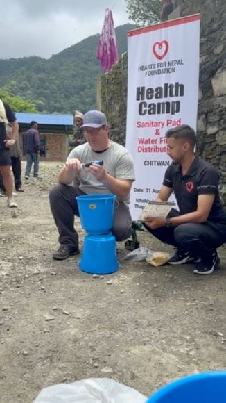 A Hearts for Nepal volunteer demonstrating a clean-water filter at the health camp