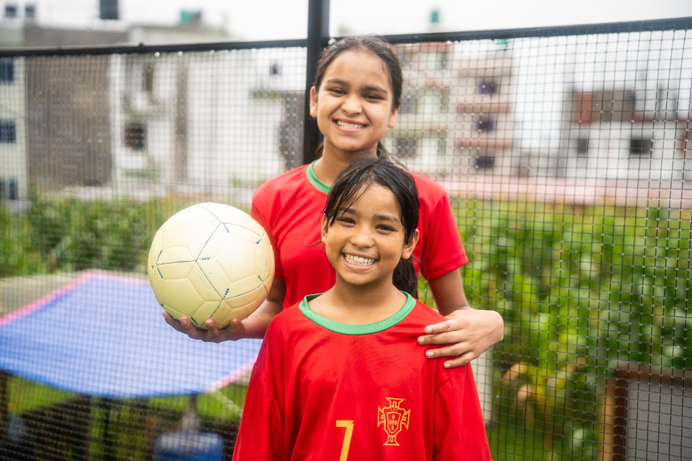 Two of our youngest girls in matching red jerseys, holding a soccer ball